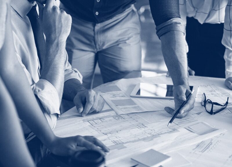 close-up of man's hand holding pencil, table covered in papers